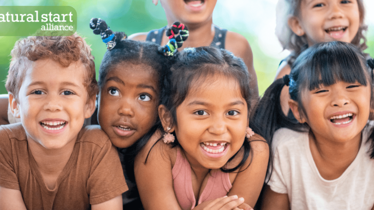 A group of six kids huddled together and smiling. The "Natural Start Alliance" logo is at the top right