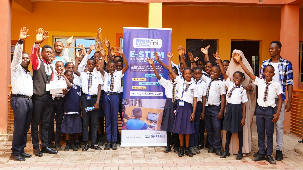 Students pose in front of a STEM workshop sign.