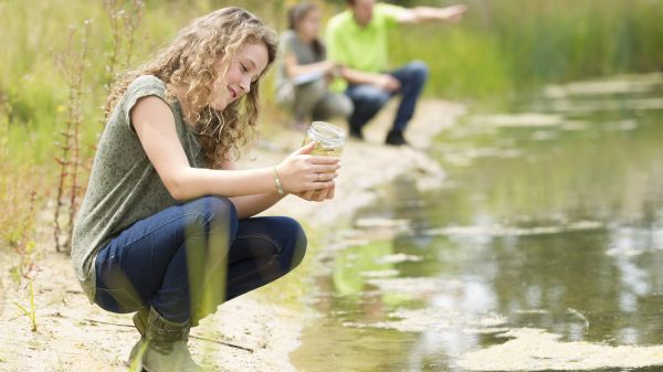 Young people at lake shore collecting water sample