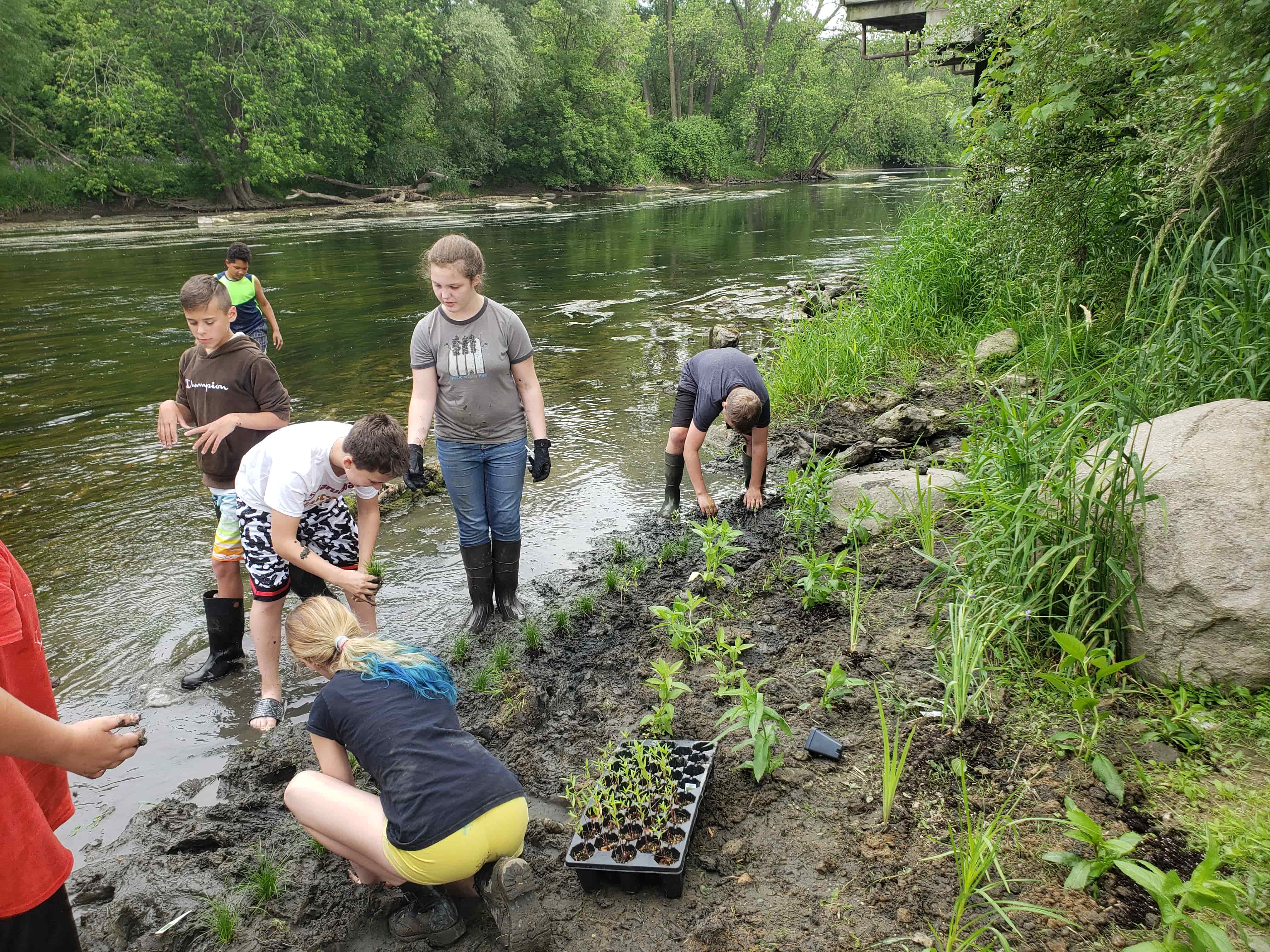 group of students near river planting