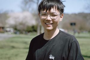 A picture of Tim Jia wearing a black shirt, smiling outdoors.