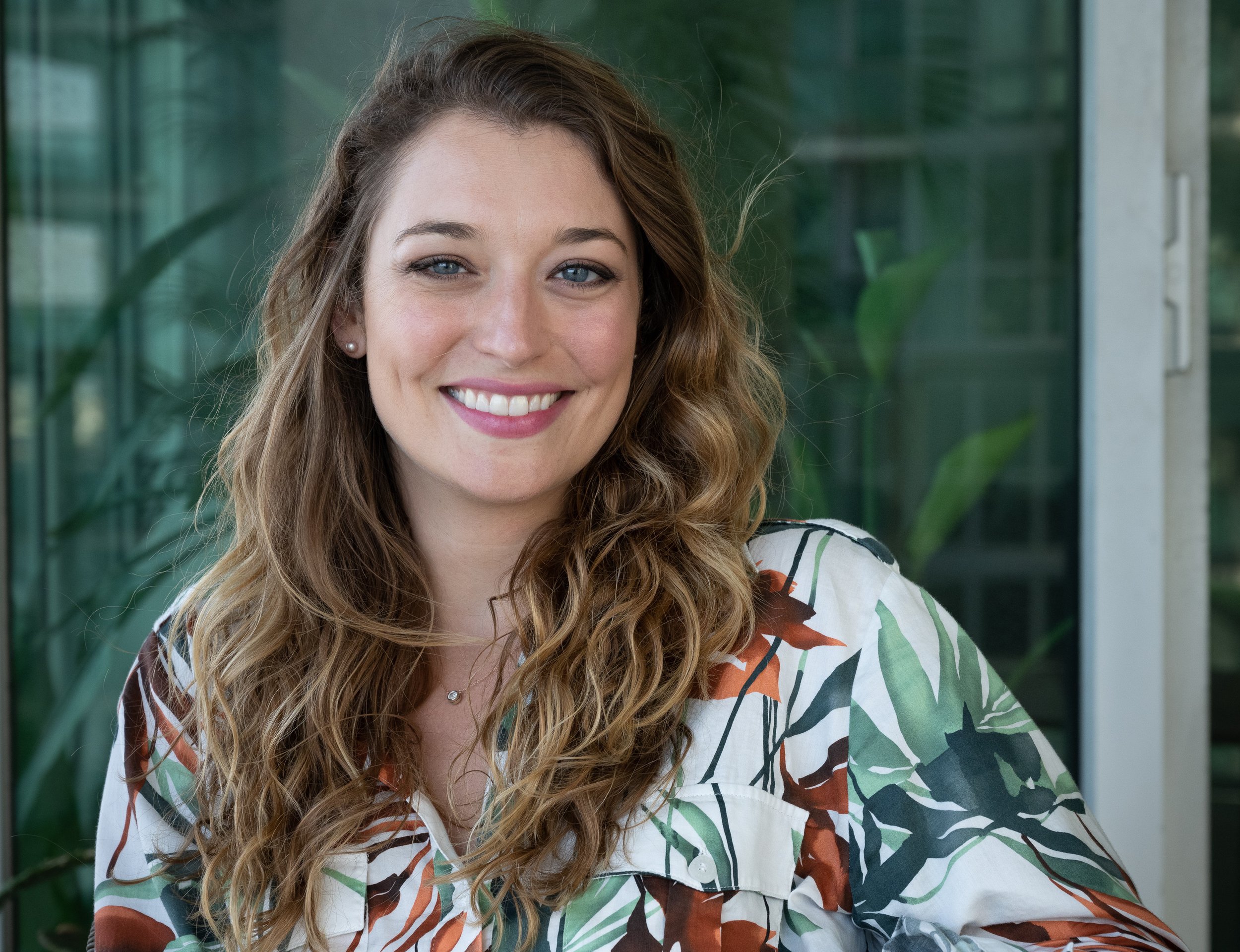 Dr. Alizé Carrere is wearing a floral shirt and smiling toward the camera