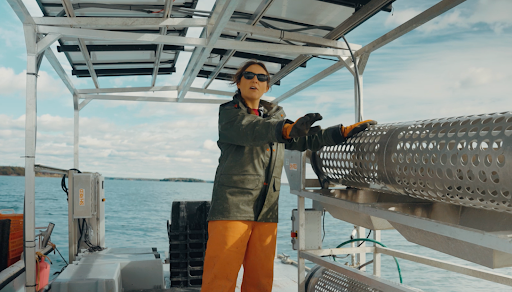 Alicia wearing sunglasses, shows off a metal tumbler in the work barge.