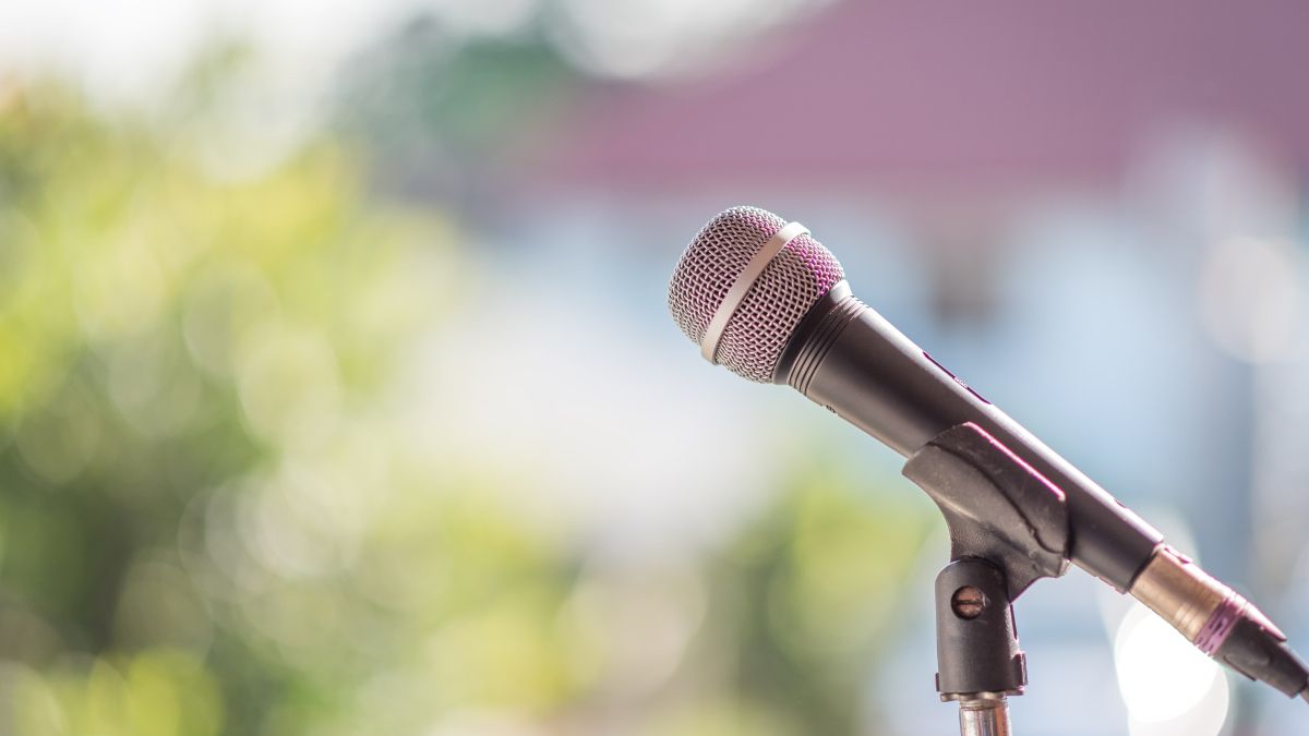 Microphone in a stand over blurred background of green trees
