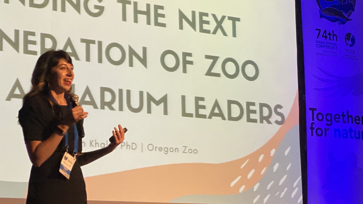 Kathayoon Khalil stands in front of a large screen, presenting on the next generation of zoo and aquarium leaders.