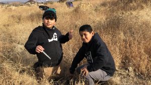 Two 5th grade students in black hoodies pose for camera. They are in the middle of restoring shrub steppe habitat in Eastern Washington.