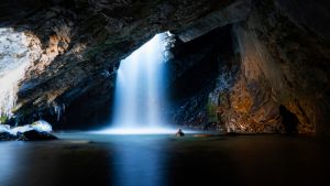 Waterfall dropping down from a hole inside of a cave on a cold autumn day in Big Cottonwood Canyon located in Utah.