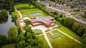 Aerial drone image of a modern and sustainable school with solar panels on the roof reducing CO2 emissions for a better environment.