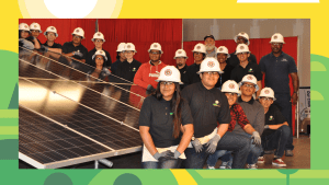 A group of people with white hard hats posing for a photo next to a large solar panel