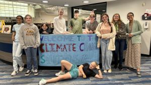 A group photo of students from the Climate Ed Student Leadership Team in front of a banner that says, Welcome to the climate change solutions museum 
