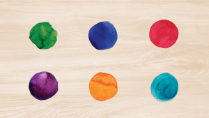 Six single paintdrops, ranging from green to blue, on a wooden background