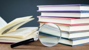 Stack of journals and a magnifying glass on a wooden table