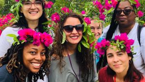 Photo of six people with pink flowers in their hair.