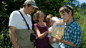 A group of students examine a large sample of water from the Karnowsky Creek with US Forest Service Water Scientist at Karnowsky Creek on the Siuslaw National Forest