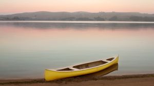 Yellow canoe on the shore of Tomales Bay at dusk with pastel colors and glassy water