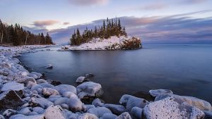 Snow covered island on Lake Superior during sunset.