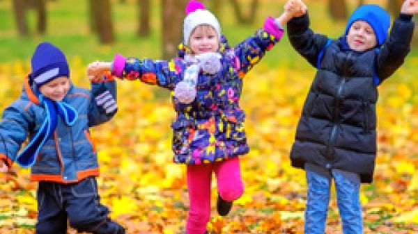 three young children in woods with yellow leaves on ground