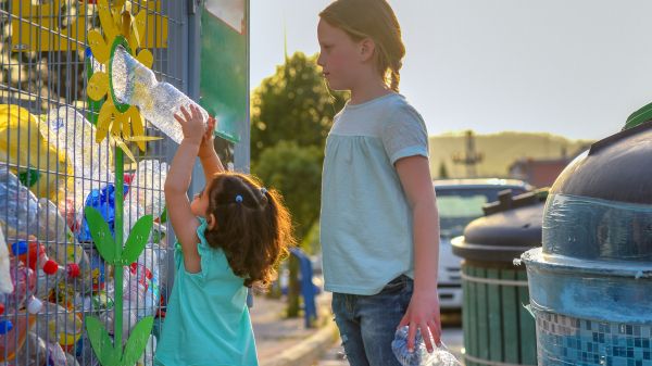 Two kids recycling plastic bottles