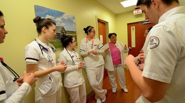 Germanna Community College's Nursing program instructor Phyllis Smith (MSN, RN) (background, center, pink blouse) reviews patient procedure with nursing students at the McGuire V.A. Medical Outpatient Clinic in Fredericksburg, Va. on Tuesday, December 2, 2014. 