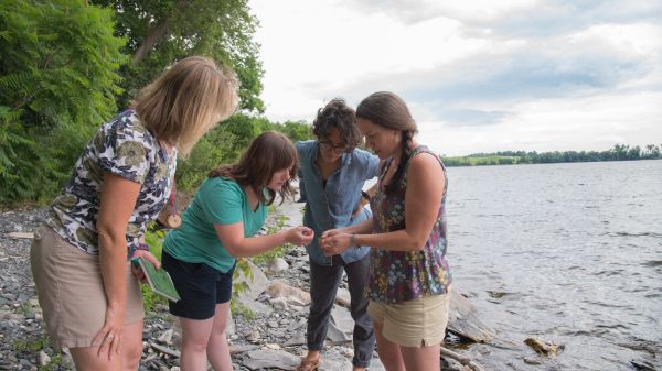 A group of educators learning on a rocky lakeshore