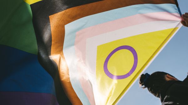A person holds LGBTI+ flag behind them