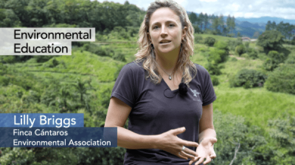 Lilly Briggs speaking, tropical forest in the background. "Environmental Education" "Lilly Briggs, Finca Cántaros Environmental Association"