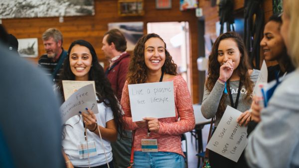 Group of students at an environmental conference holding up a sign that says "Live a Plastic Free Life" 