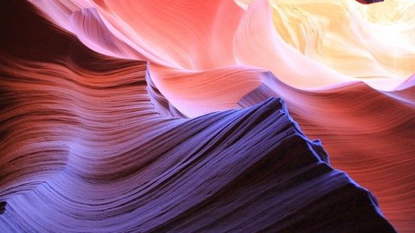 Colorful, wavy sedimentary rock awash in hues of purple, red, and yellow.