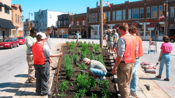 A group of people at a small community garden on an intersection island