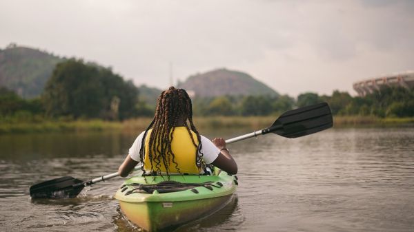 A person in a yellow life jacket paddles in a kayak