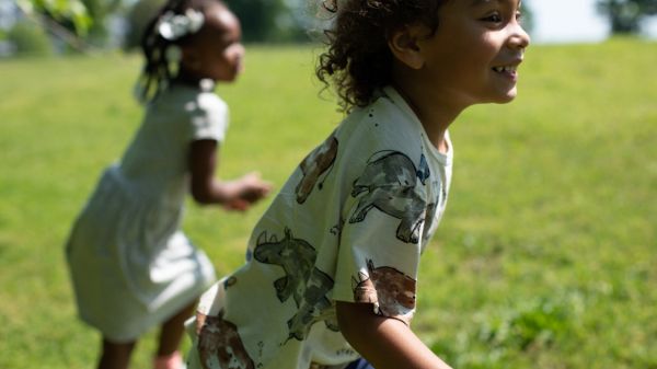 Two kids running outside on grass