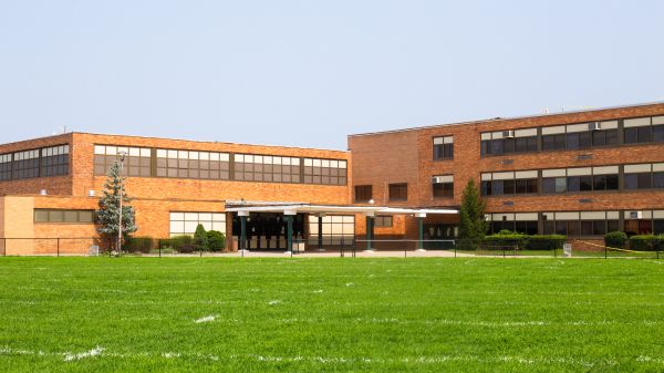 School sitting behind a field of bright, green grass.
