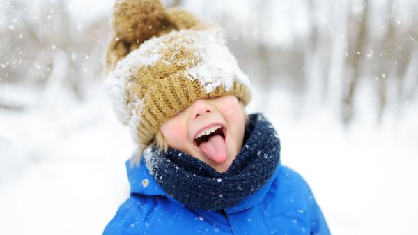 little boy in snow with hat covering eyes and tongue sticking out