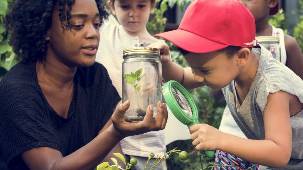 teacher showing young students plant in jar