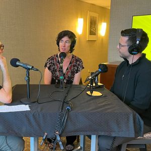 Gerry Ellis, Juliet Grable, and James Parker sit around a hotel table while recording for The World We Want podcast