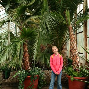 young student standing in greenhouse