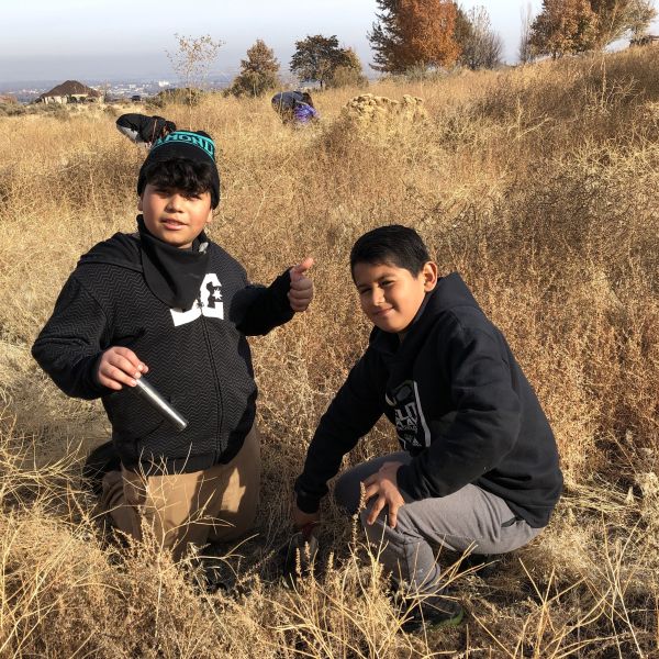 Two 5th grade students in black hoodies pose for camera. They are in the middle of restoring shrub steppe habitat in Eastern Washington.