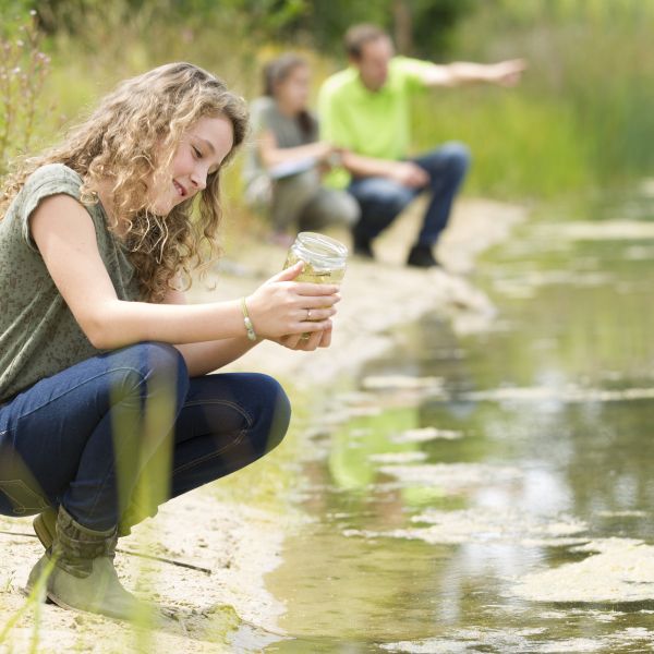 Young people at lake shore collecting water sample