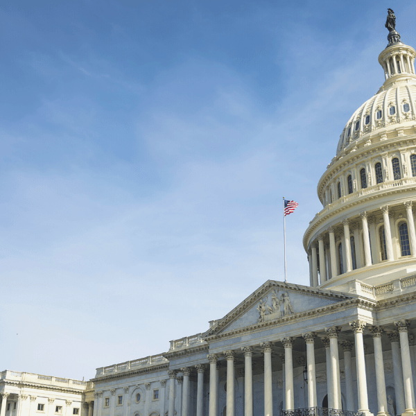 Image of the United States Capitol. The building fits in the bottom right side of the image, while a blue sky with light clouds rises up behind it. 