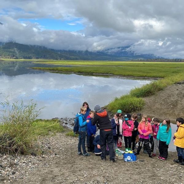 Author Jade with a group of children near a lake and with mountains in the back.