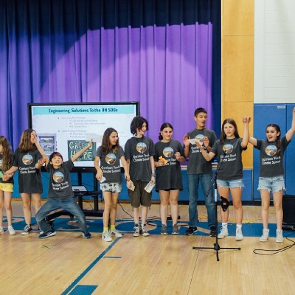 A row of students in a gynasium hold hands and take a bow