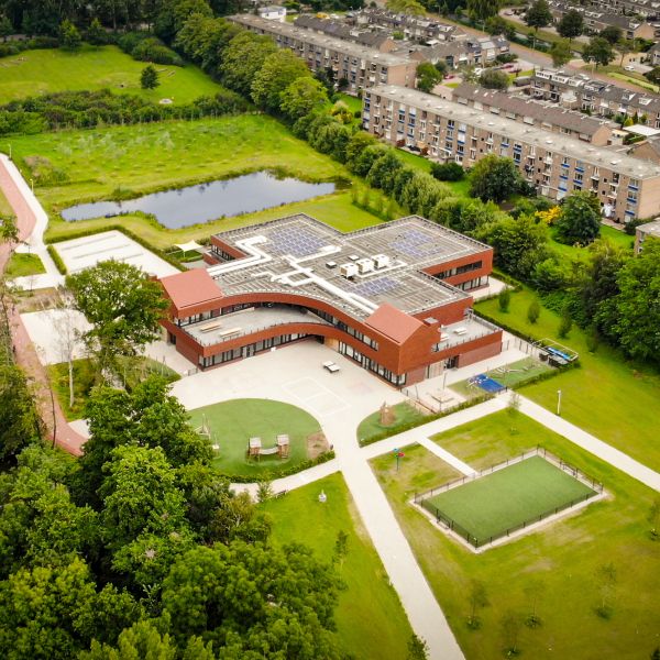 Aerial drone image of a modern and sustainable school with solar panels on the roof reducing CO2 emissions for a better environment.