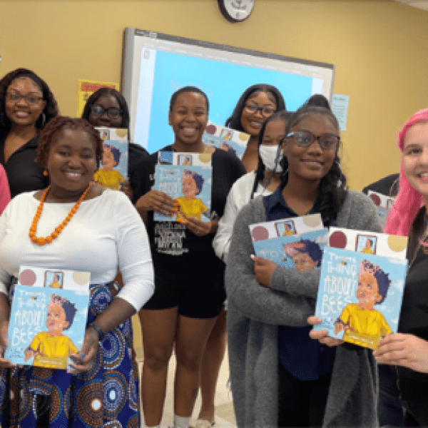 A group of preservice teachers hold up books about bees to promote literacy