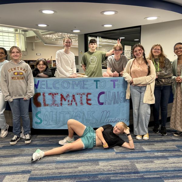 A group photo of students from the Climate Ed Student Leadership Team in front of a banner that says, Welcome to the climate change solutions museum 